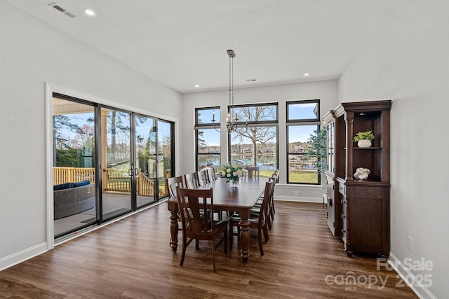 dining room with dark wood-style floors, visible vents, a notable chandelier, and baseboards