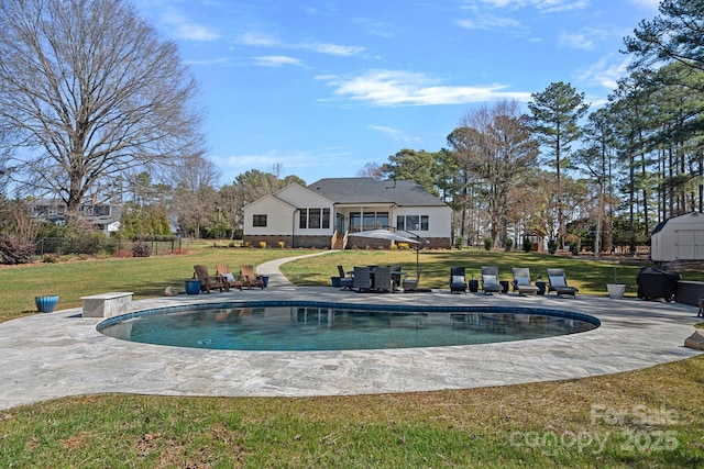 rear view of property featuring an outbuilding, a patio, a storage shed, a yard, and an outdoor pool