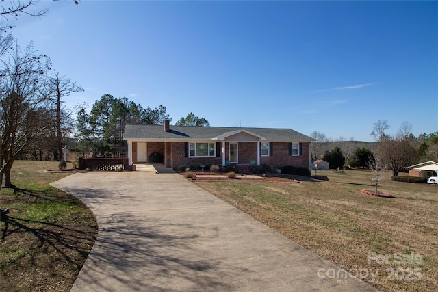 ranch-style home featuring brick siding, a chimney, concrete driveway, and a front lawn