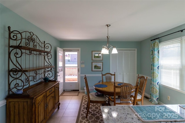 dining area featuring light tile patterned floors, a healthy amount of sunlight, baseboards, and a chandelier