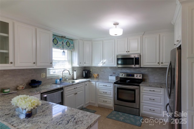 kitchen with decorative backsplash, white cabinets, appliances with stainless steel finishes, and a sink