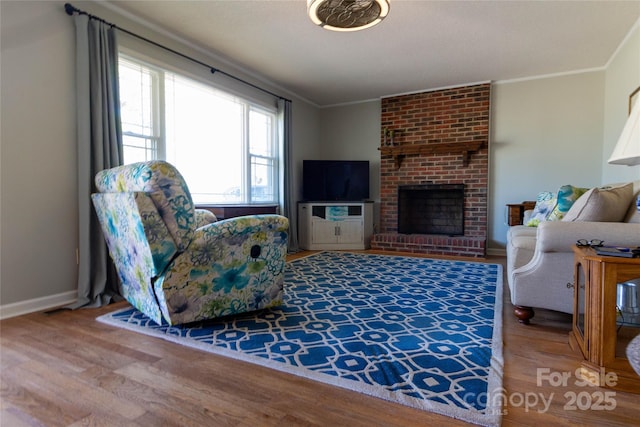 living room with a fireplace, wood finished floors, baseboards, and ornamental molding