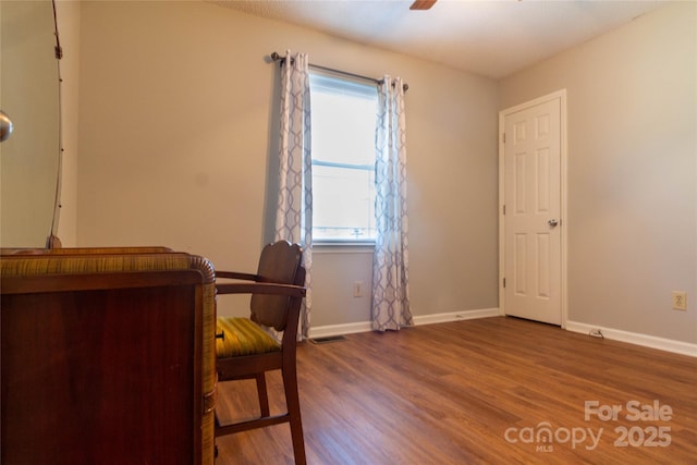 office featuring ceiling fan, visible vents, baseboards, and wood finished floors