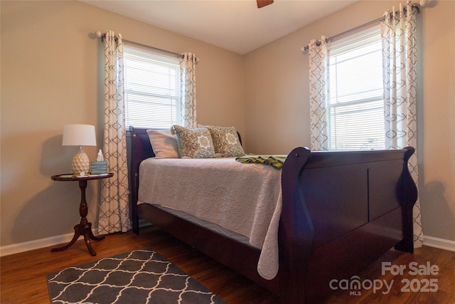 bedroom featuring multiple windows, baseboards, and wood finished floors