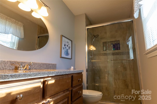 full bathroom featuring a stall shower, toilet, and vanity