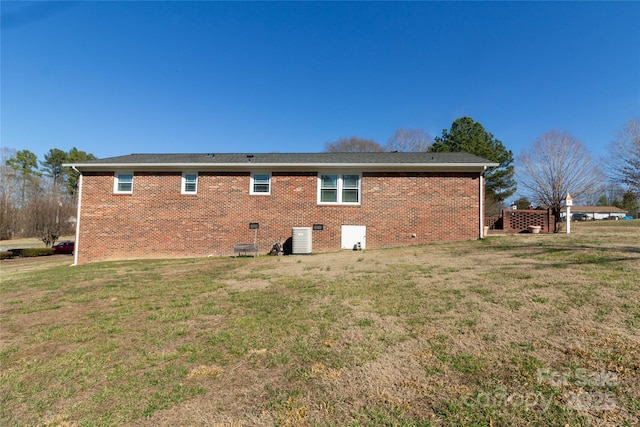 rear view of house with crawl space, central air condition unit, a lawn, and brick siding