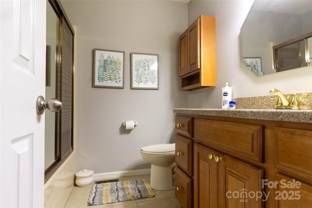 bathroom with tile patterned floors, toilet, shower / bath combination with glass door, baseboards, and vanity