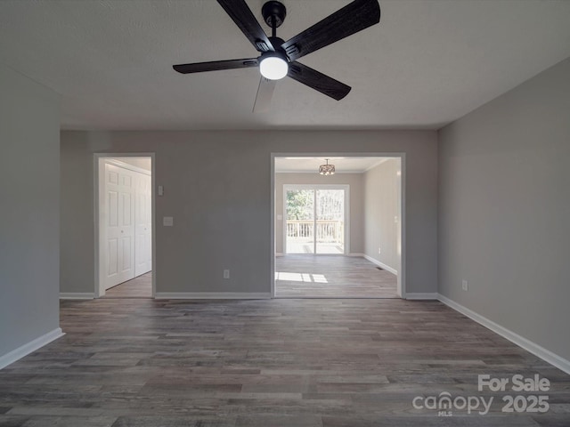 unfurnished room featuring a ceiling fan, baseboards, and wood finished floors