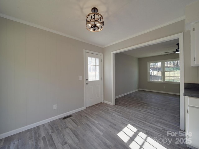 interior space featuring plenty of natural light, wood finished floors, visible vents, and crown molding