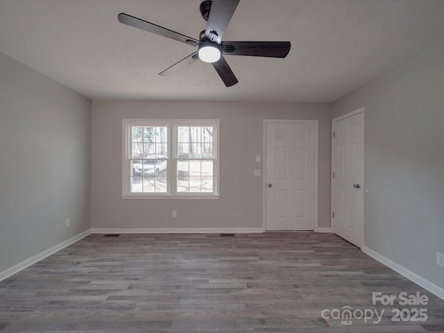 unfurnished room featuring a ceiling fan, a textured ceiling, baseboards, and wood finished floors