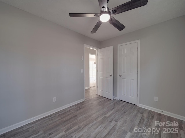 unfurnished bedroom with ceiling fan, wood finished floors, and baseboards