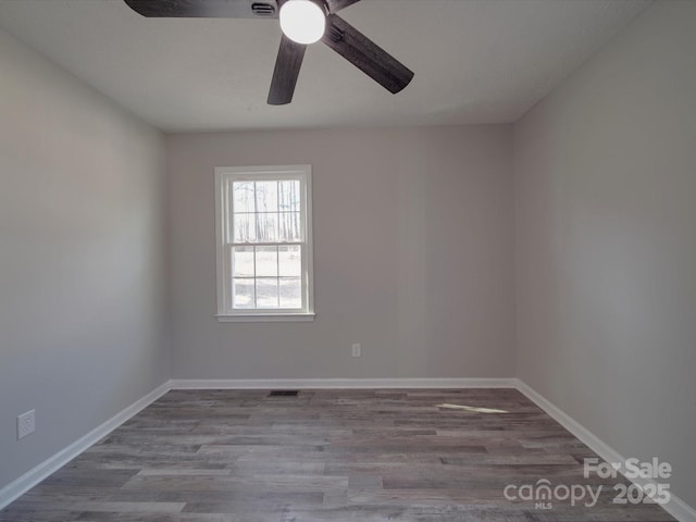 unfurnished room with baseboards, visible vents, and wood finished floors