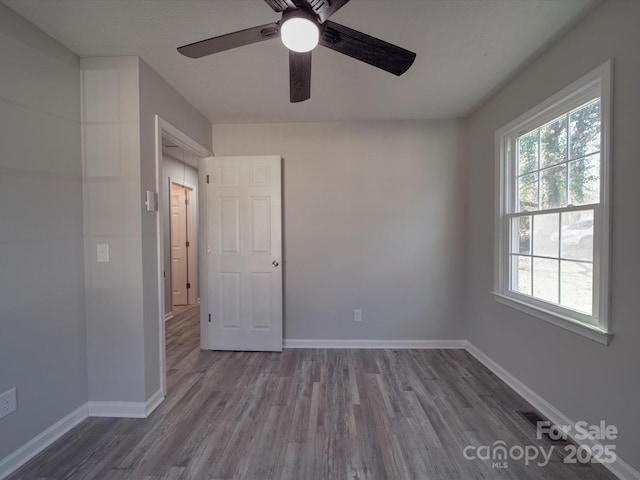 interior space featuring ceiling fan, wood finished floors, and baseboards