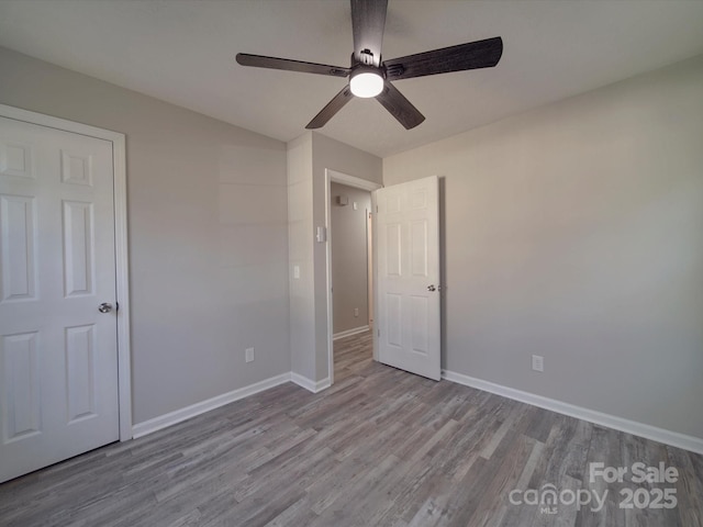 unfurnished bedroom featuring wood finished floors, a ceiling fan, and baseboards