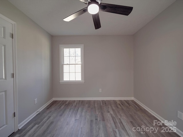 spare room featuring wood finished floors, a ceiling fan, and baseboards