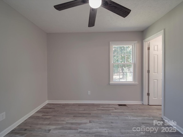 unfurnished room with a textured ceiling, baseboards, and wood finished floors