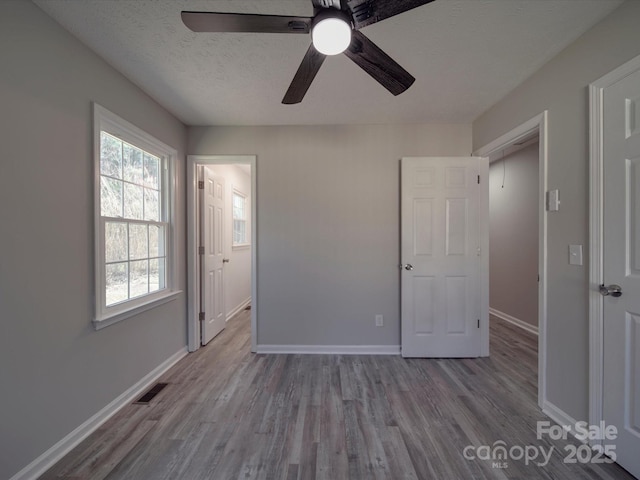 unfurnished bedroom with a textured ceiling, baseboards, and wood finished floors