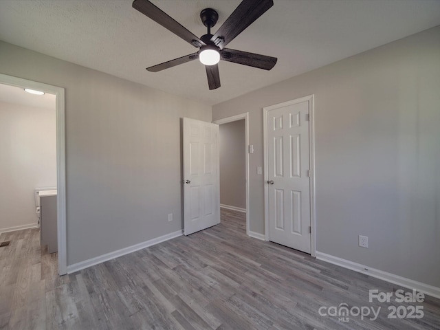 unfurnished bedroom with a ceiling fan, baseboards, and wood finished floors