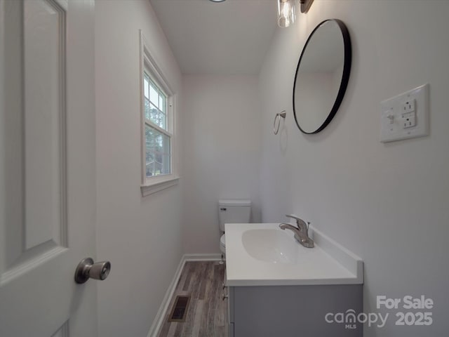 bathroom with baseboards, visible vents, toilet, wood finished floors, and vanity