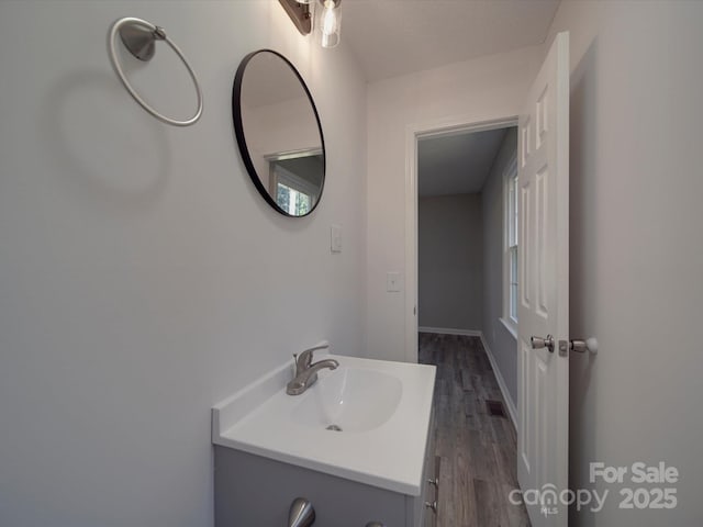 bathroom featuring visible vents, wood finished floors, vanity, and baseboards