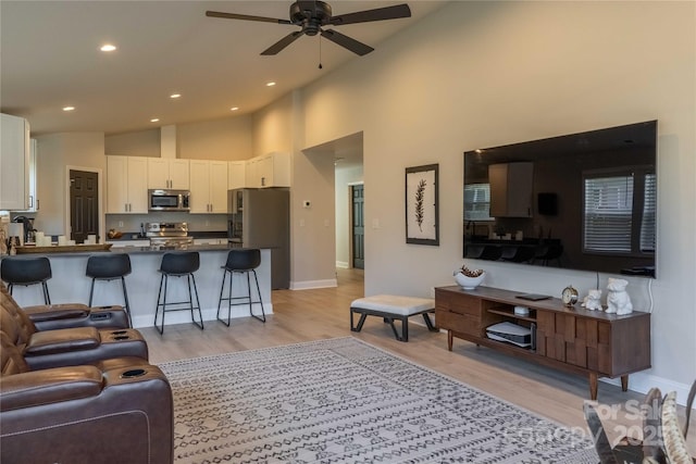 living area featuring light wood-type flooring, ceiling fan, high vaulted ceiling, and recessed lighting