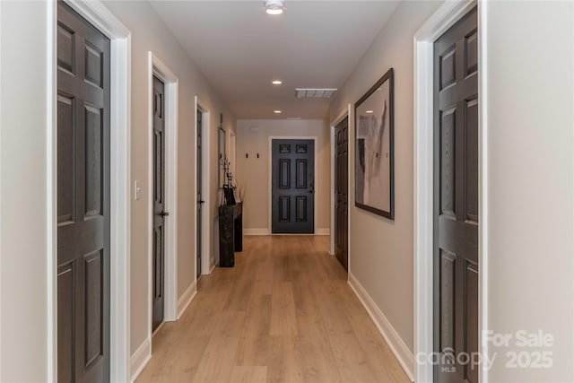 hall featuring light wood-type flooring, visible vents, baseboards, and recessed lighting