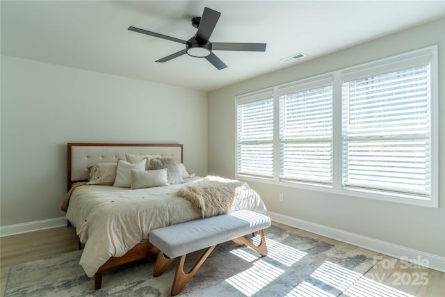 bedroom featuring a ceiling fan, baseboards, visible vents, and wood finished floors