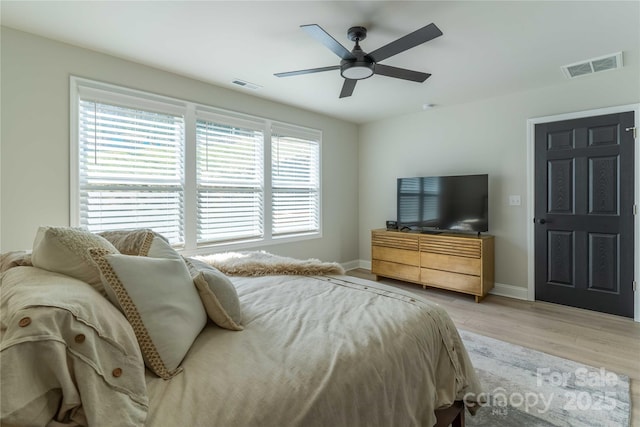 bedroom featuring light wood-type flooring, baseboards, visible vents, and a ceiling fan