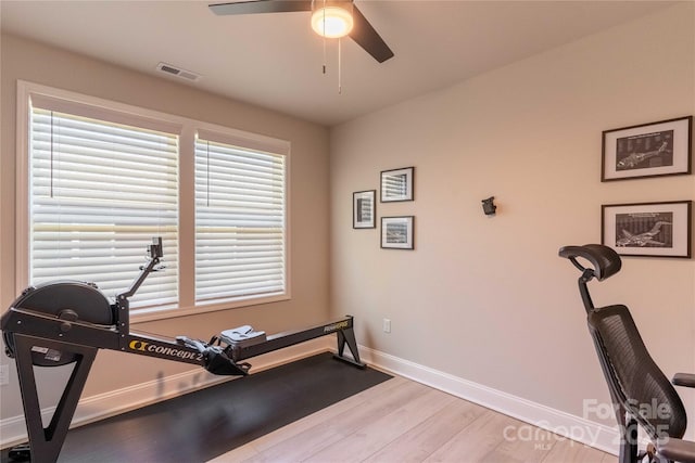 exercise room with baseboards, visible vents, ceiling fan, and wood finished floors