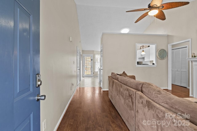 hallway featuring lofted ceiling, dark wood-style flooring, and baseboards