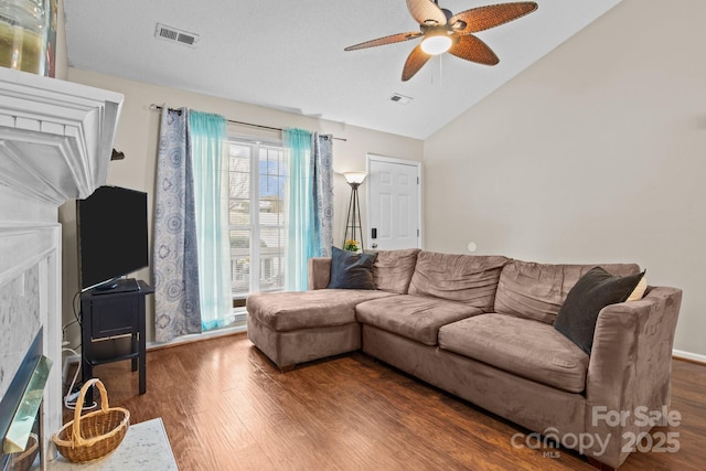 living room featuring lofted ceiling, wood finished floors, visible vents, and a ceiling fan