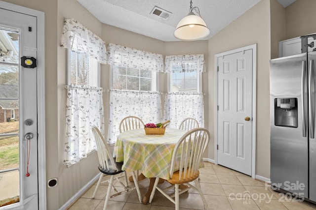 dining space featuring light tile patterned floors, plenty of natural light, visible vents, and a textured ceiling