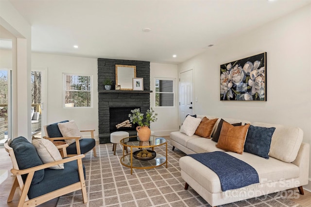 living room with baseboards, a stone fireplace, wood finished floors, and recessed lighting