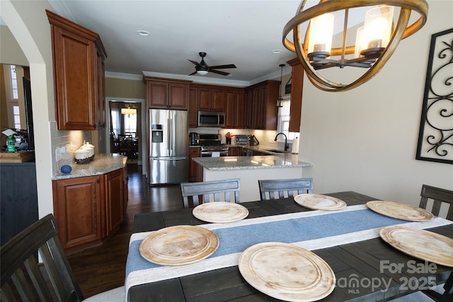 dining area featuring ceiling fan with notable chandelier, dark wood-type flooring, and crown molding