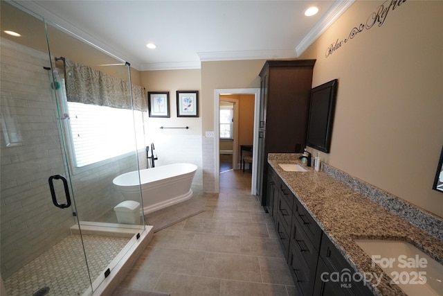 full bath with double vanity, ornamental molding, a stall shower, a sink, and a freestanding tub