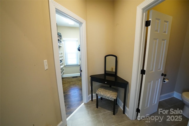 hall featuring baseboards and tile patterned floors