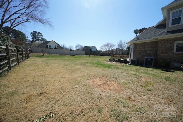 view of yard with a fenced backyard and central AC unit