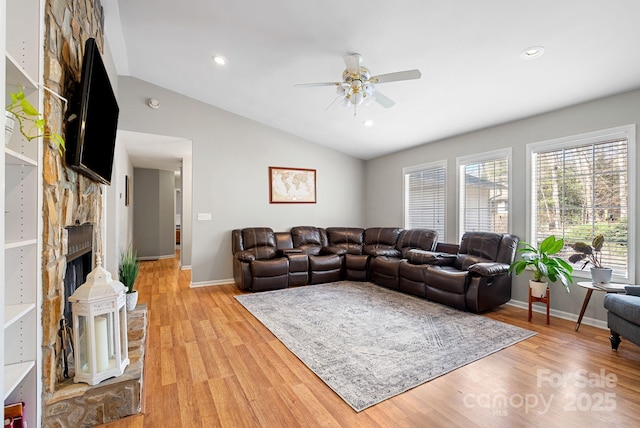 living room featuring lofted ceiling, a stone fireplace, recessed lighting, a ceiling fan, and light wood finished floors