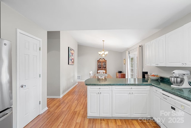 kitchen with a peninsula, white dishwasher, freestanding refrigerator, and white cabinetry