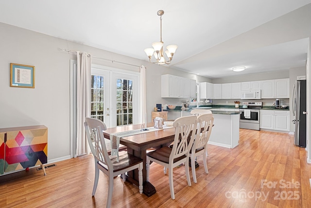 dining area featuring light wood-style flooring, a notable chandelier, visible vents, baseboards, and french doors