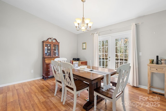 dining space with light wood-style flooring, baseboards, and an inviting chandelier