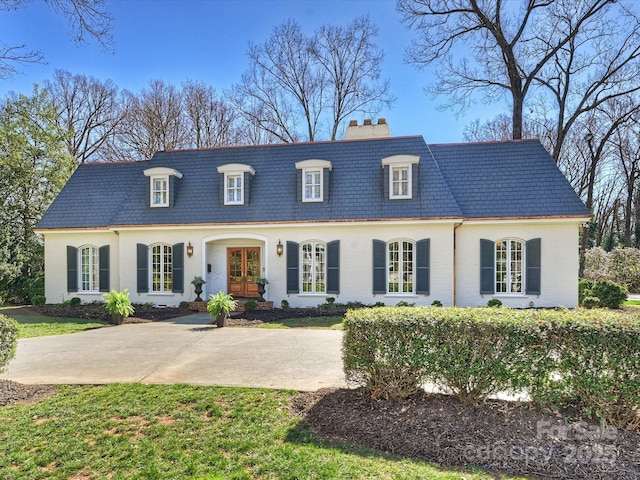 view of front of house featuring a high end roof, a chimney, mansard roof, and french doors