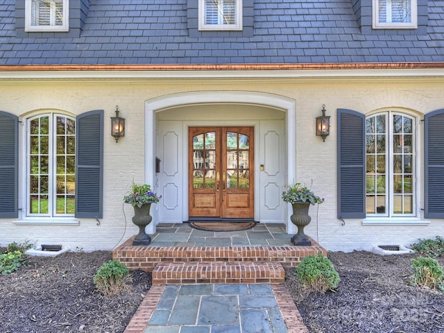 property entrance featuring french doors, brick siding, crawl space, and a high end roof