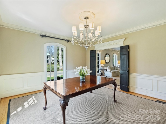 office area featuring visible vents, wainscoting, wood finished floors, an inviting chandelier, and crown molding