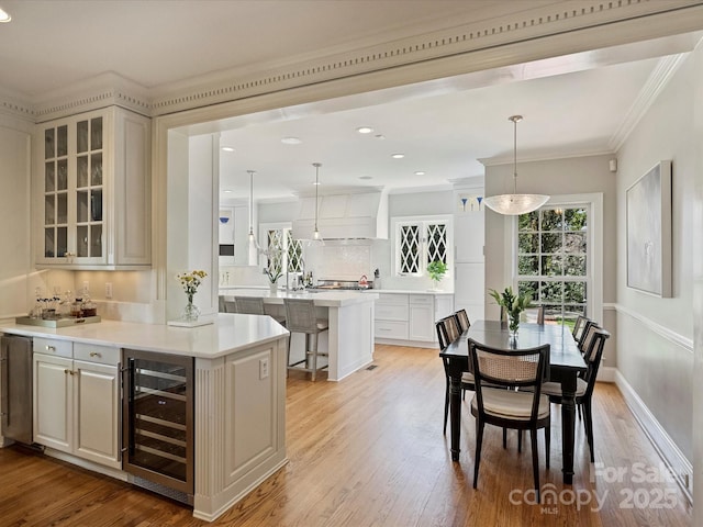 bar featuring beverage cooler, crown molding, light wood-style flooring, and decorative backsplash