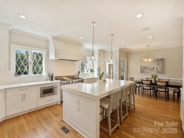 kitchen featuring visible vents, light wood-style floors, light countertops, appliances with stainless steel finishes, and custom range hood