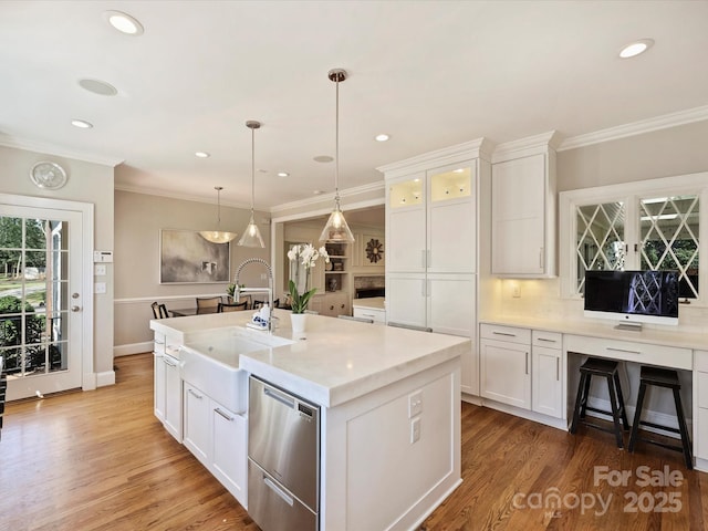 kitchen featuring a kitchen island with sink, white cabinets, a sink, and wood finished floors