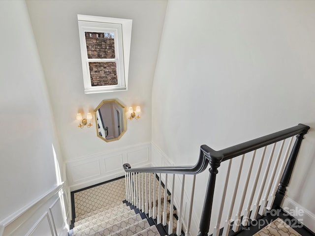 stairway featuring a wainscoted wall and a decorative wall