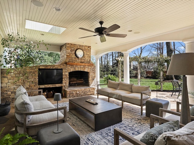 view of patio / terrace with an outdoor living space with a fireplace and a ceiling fan