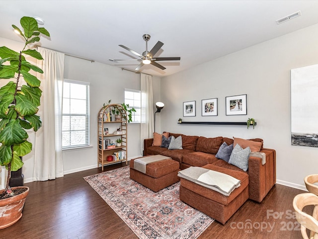 living room with dark wood-type flooring, visible vents, ceiling fan, and baseboards